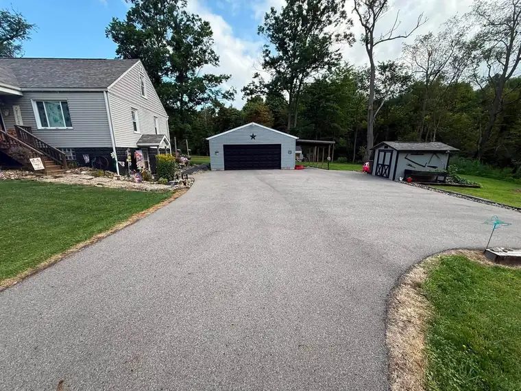 A grey, worn asphalt driveway showing its age before repair and sealing