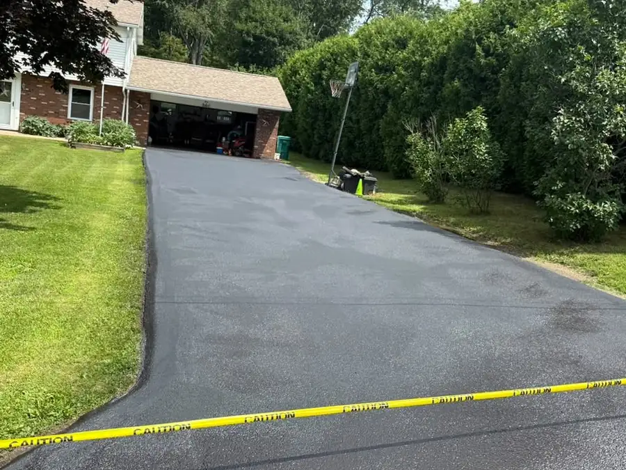 A long residential driveway sealed black with barricade tape across the entrance